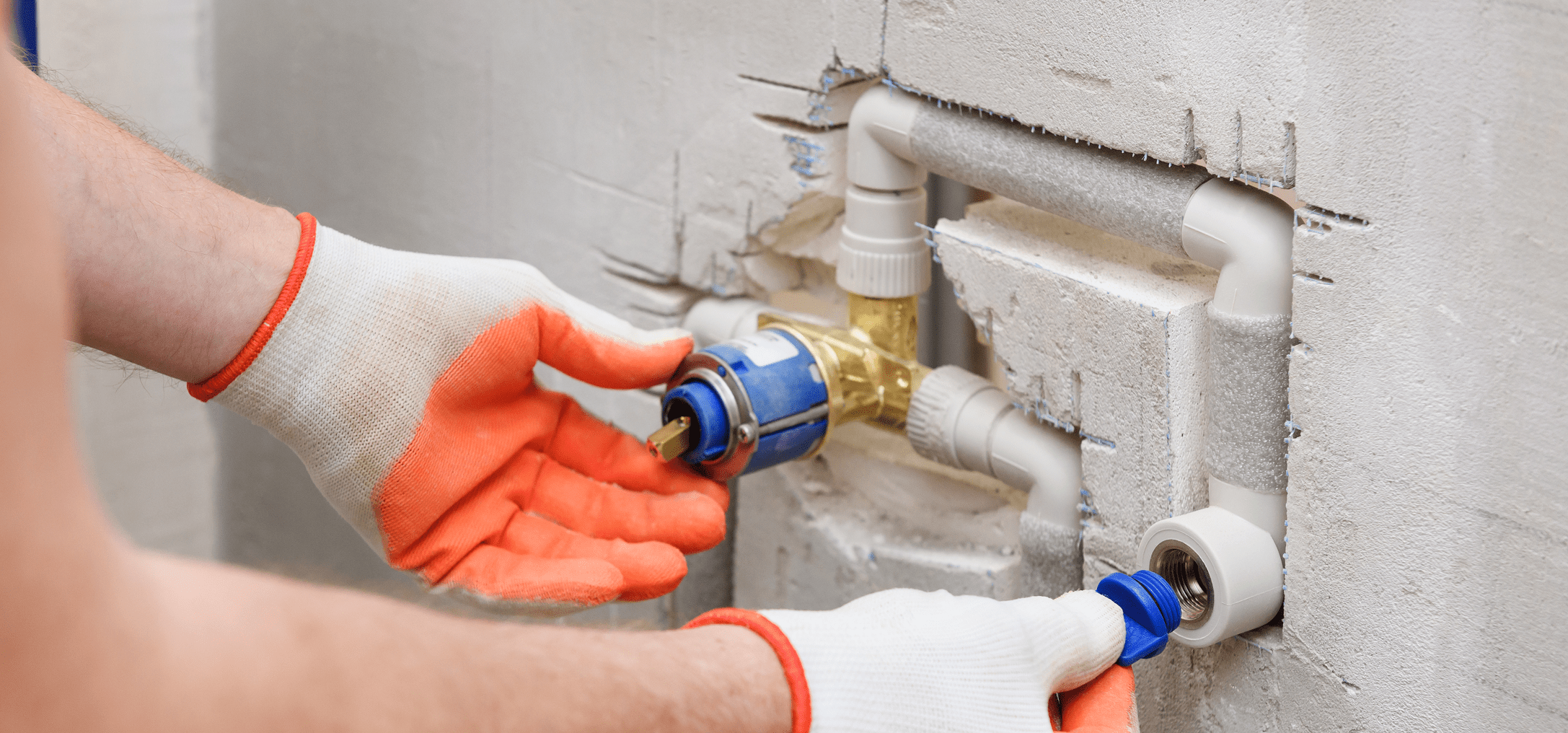 Worker wearing gloves adjusts pipe fittings