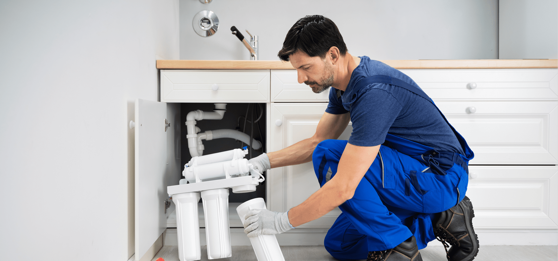 Man working on under-sink water filtration